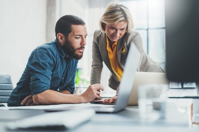 A man and a woman looking at a laptop screen.